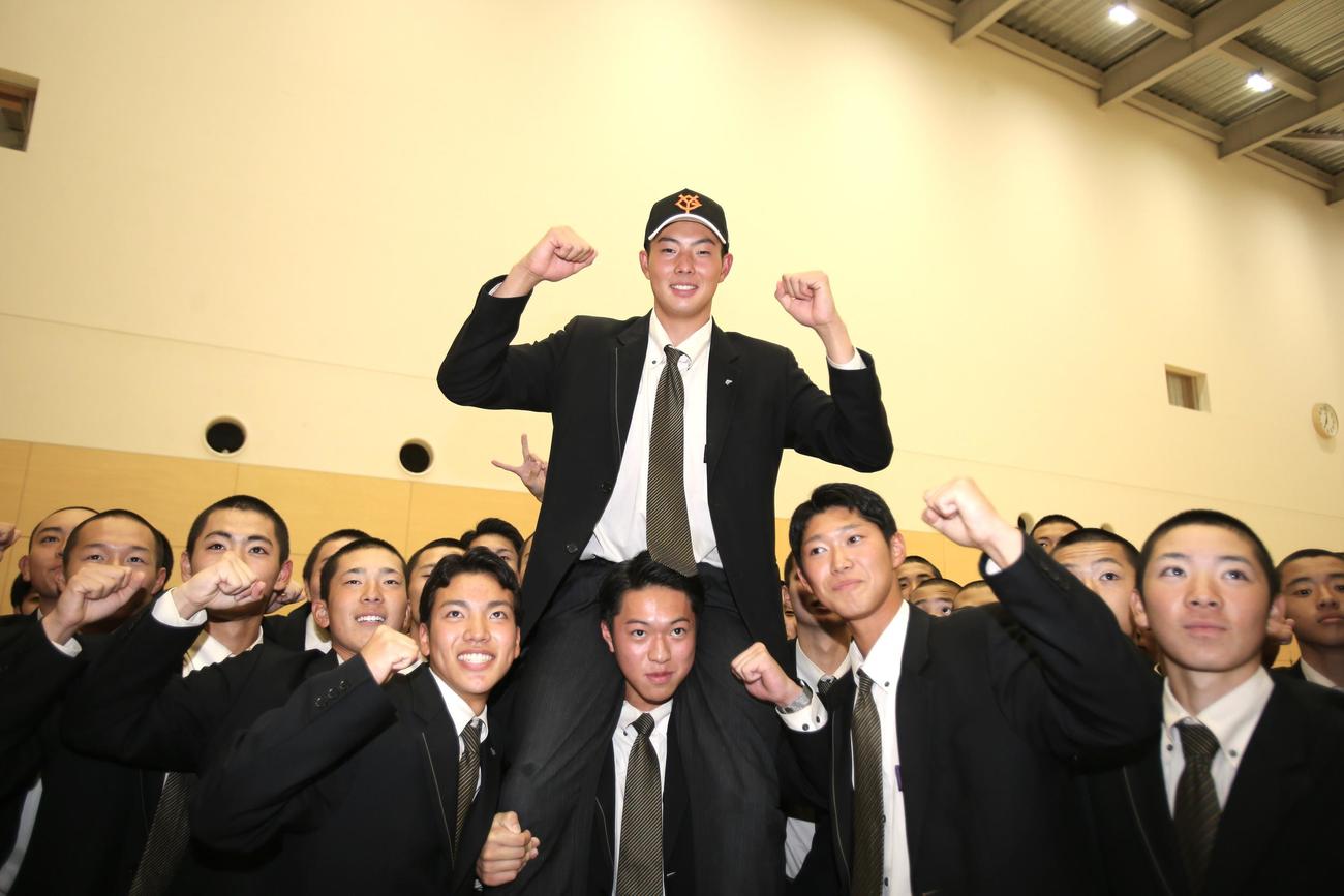 巨人から4位指名を受けた北星学園大付の石田は、チームメートに肩車してもらいガッツポーズ（撮影・中島洋尚）