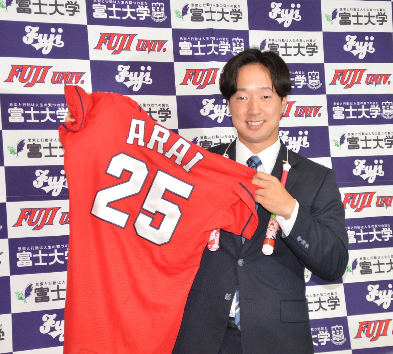 広島から2位で指名された富士大・佐藤は広島新井監督のユニホームを手に記念撮影（撮影・浜本神威）