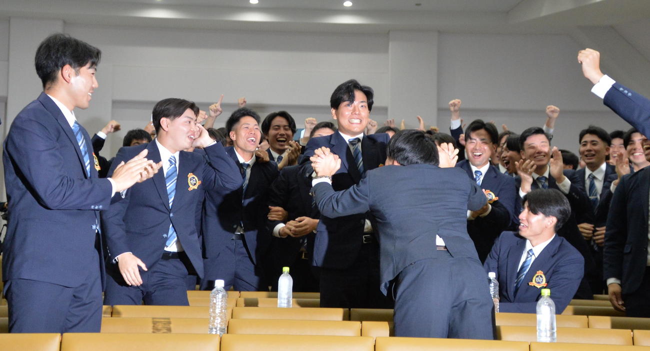 広島から4位で指名された富士大・渡辺（中央）は驚いた表情を浮かべる（撮影・浜本神威）