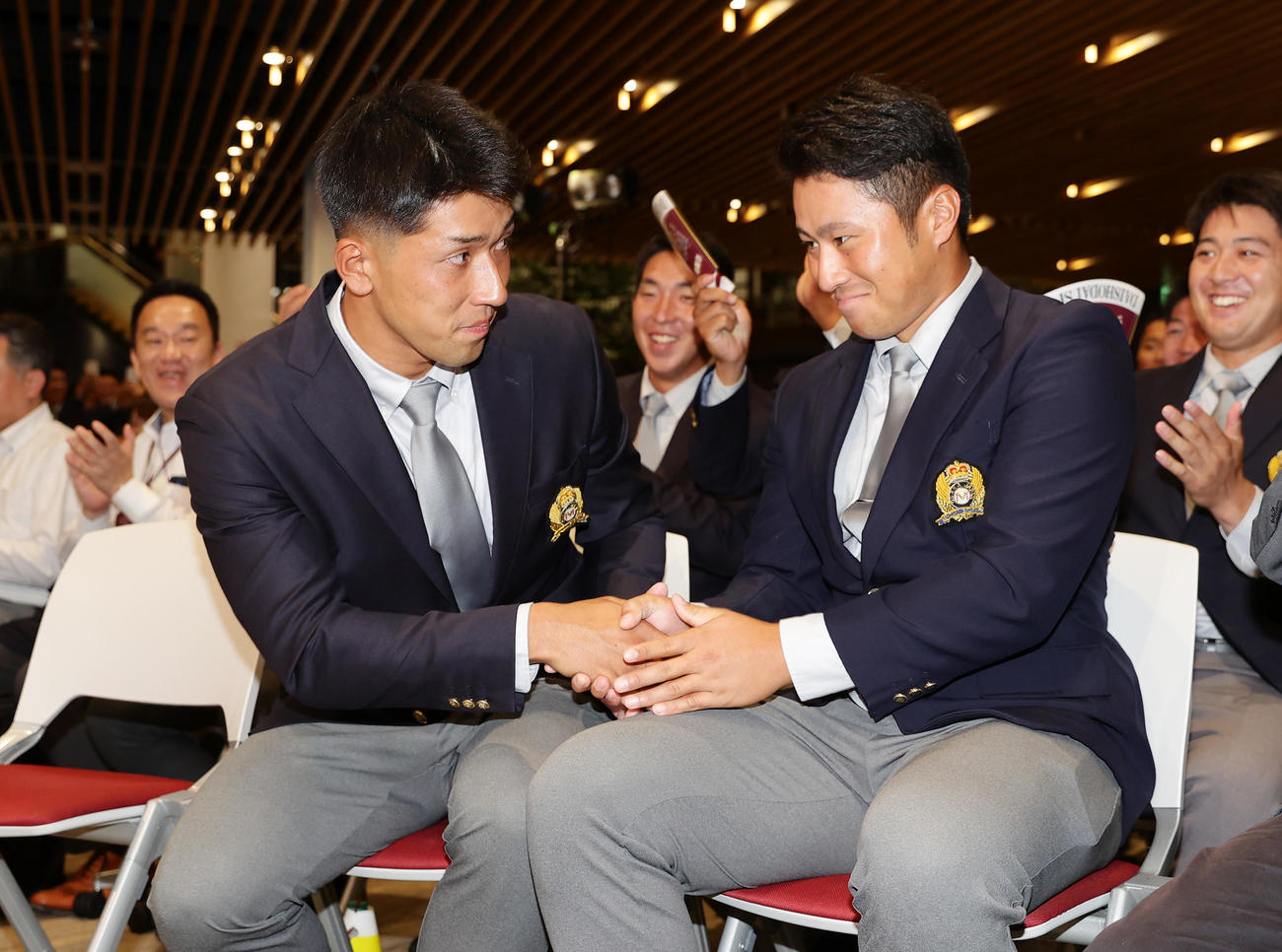 ソフトバンクから育成9位で指名を受け、西武から2位指名を受けた大商大・渡部（右）と握手を交わす岡田（撮影・前田充）