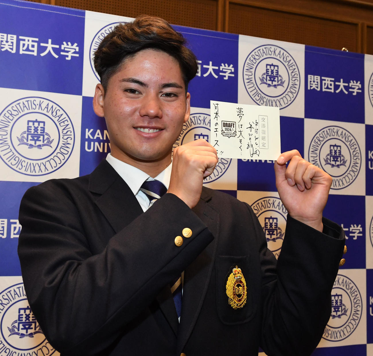 中日井上監督（右）から贈られた「交渉権確定」のくじを手に笑顔を見せる関大・金丸（撮影・前岡正明）