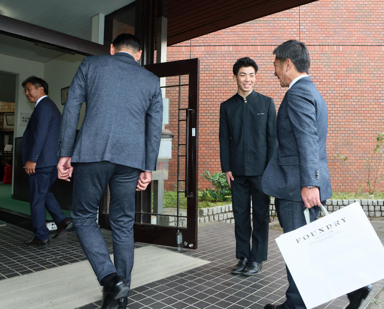ソフトバンクの永井本部長（手前左）と稲嶺スカウト（右）を出迎える村上。左端は岡本監督（撮影・加藤哉）