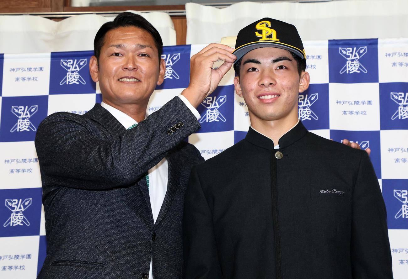 ソフトバンクの指名あいさつを受けた神戸弘陵・村上は、永井本部長（左）から帽子をかぶせてもらう（撮影・加藤哉）