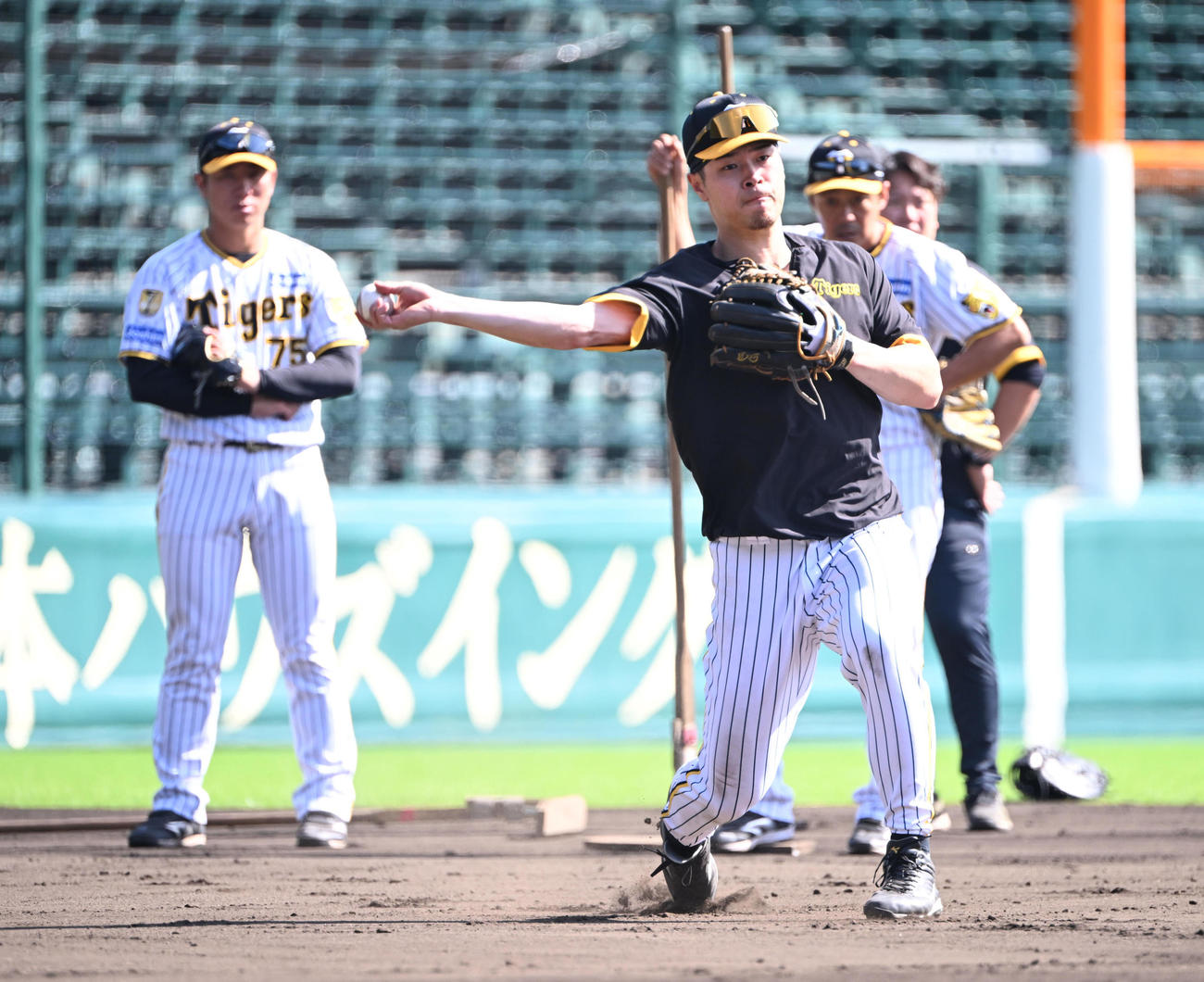田中（左）と藤本の両コーチの指導を受けながら守備練習する阪神佐藤輝（撮影・和賀正仁）