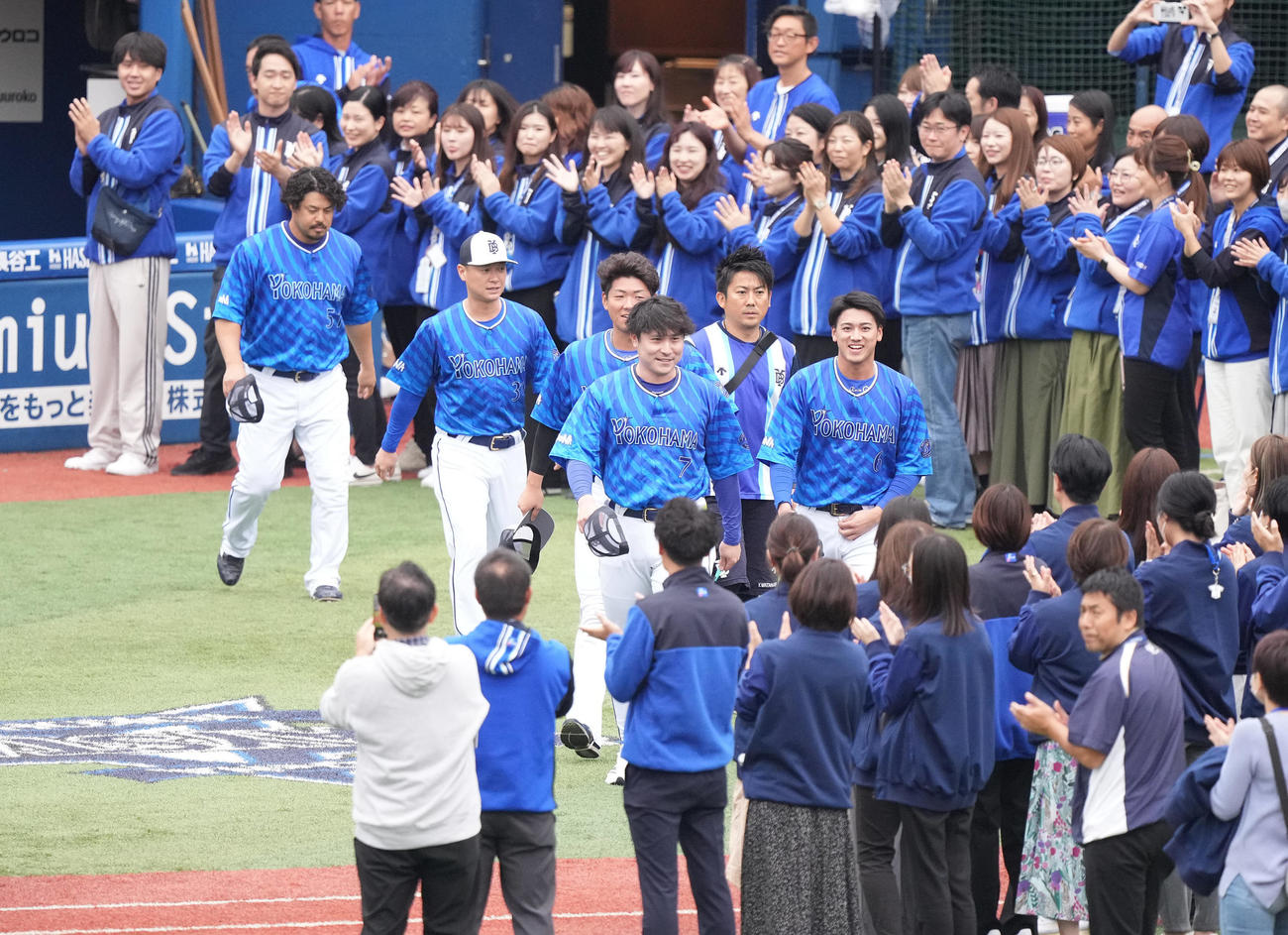 スタッフが作る花道を通り練習に向かうDeNA佐野（前列左）、森敬（同右）ら（撮影・鈴木みどり）