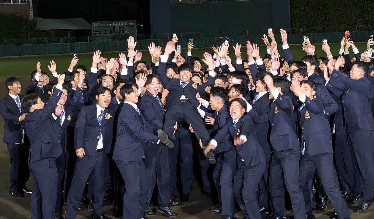 24日、オリックスから外れ1位で指名された富士大・麦谷（中央）はグラウンドでチームメートに胴上げされ、満面の笑み(2024年10月24日撮影)
