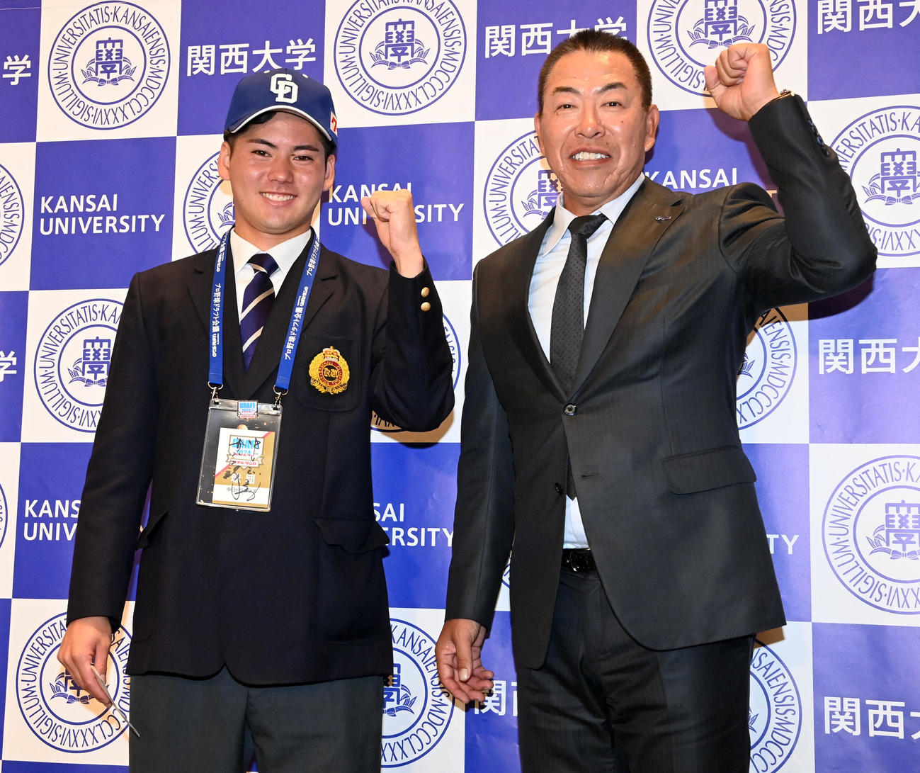 指名あいさつを受け、中日井上監督（右）と笑顔でガッツポーズを見せる関大・金丸（撮影・前岡正明）