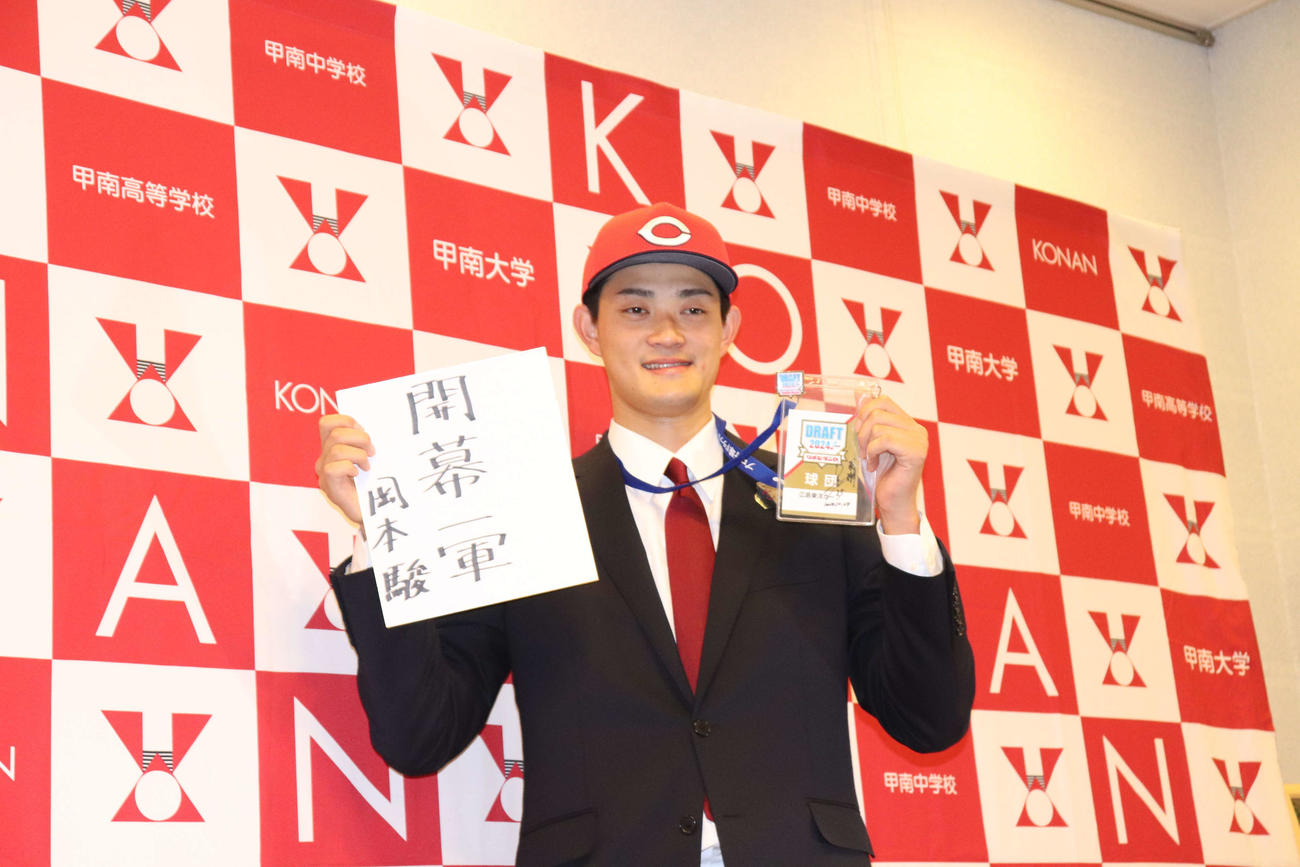 広島から3位指名を受け、新井監督の「感謝」と書かれたIDパスと自らが書いた「開幕一軍」の色紙を持つ、甲南大・岡本（撮影・中島麗）
