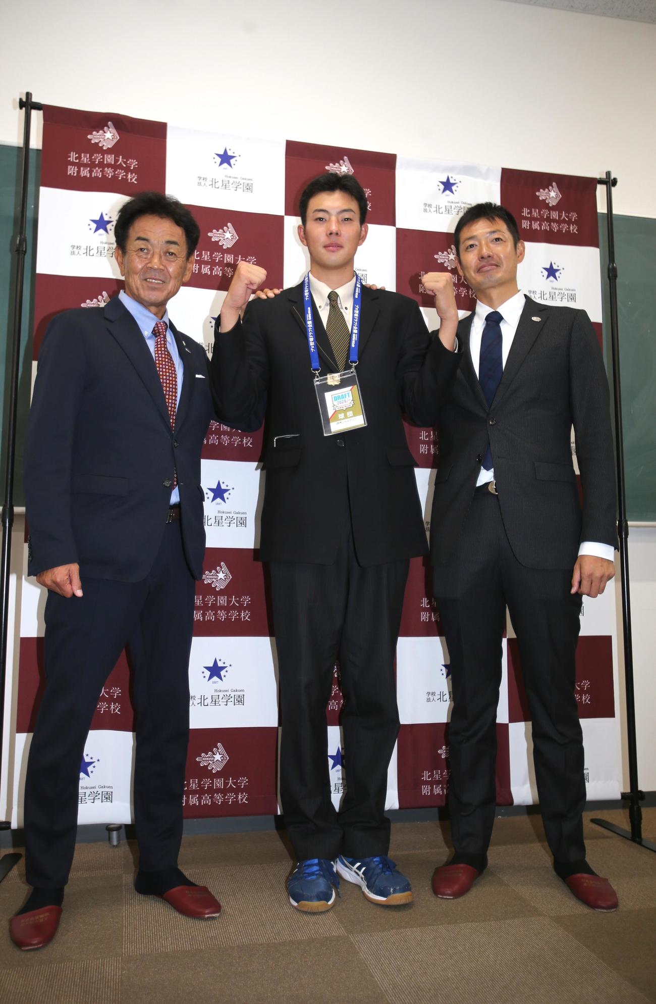 巨人4位の北星学園大付・石田（中央）は、巨人の水野スカウト部長（左）と青木スカウトの指名あいさつを受けて両腕でガッツポーズ（撮影・中島洋尚）