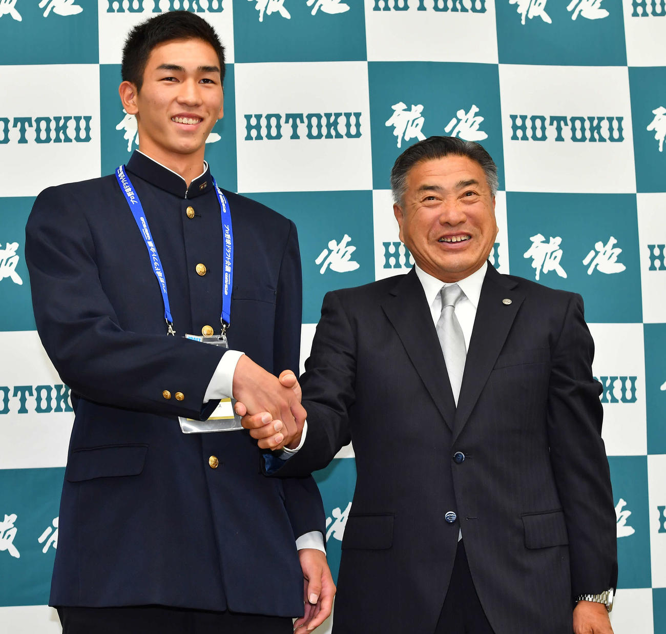 阪神2位指名の報徳学園・今朝丸（左）は熊野スカウトと握手を交わす（撮影・清水貴仁）