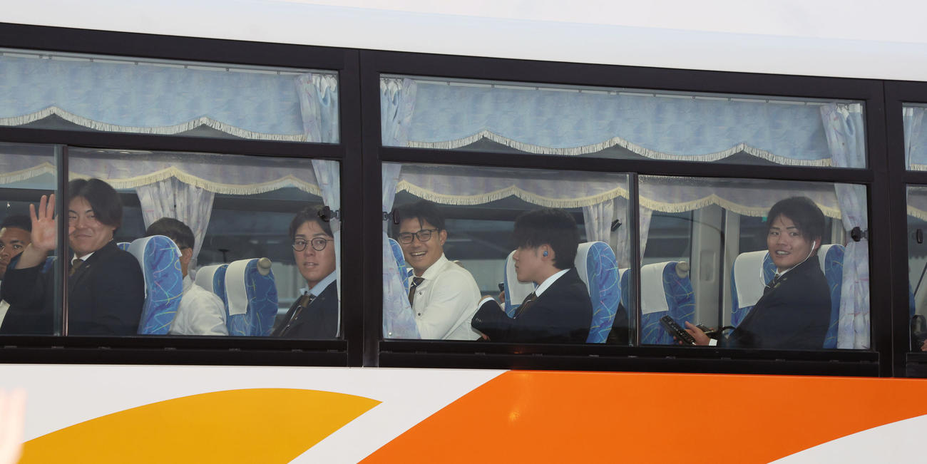 秋季キャンプを前に高知入りしファンにバス車内から手を振る前川（左）。左から2人目から豊田、栄枝、富田、小野寺（撮影・加藤哉）