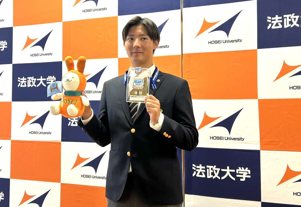 日本ハム6位指名のあいさつを受け、法大マスコットキャラクターえこぴょんと関係者パスを両手に笑顔を見せる法大・山城（撮影・佐瀬百合子）