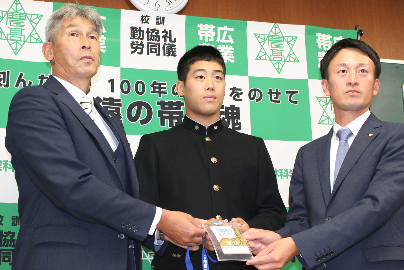 日本ハム白井スカウト（左）から指名あいさつを受けた育成2位の帯広農・渋谷（右は西川監督）（撮影・木下大輔）
