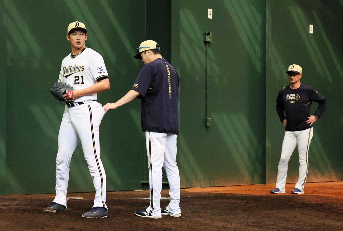 ブルペンのマウンド立つ山崎に手を伸ばす厚沢コーチ。右は岸田監督（撮影・加藤哉）