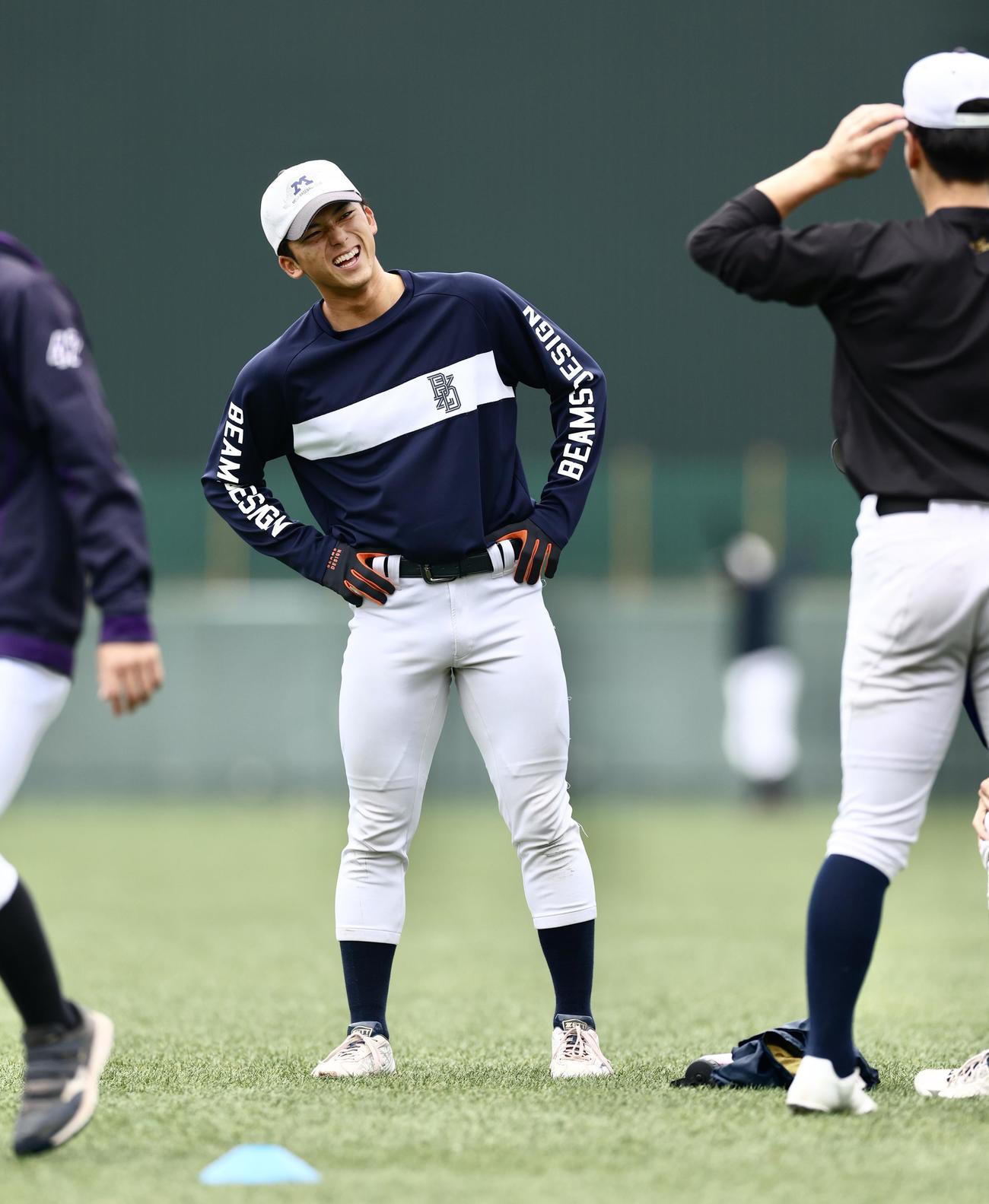 笑顔でウオーミンクアップする明大・宗山（撮影・河田真司）