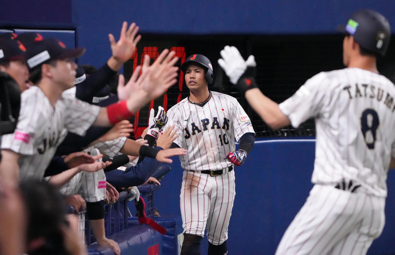 日本対オーストラリア　1回裏日本無死一、三塁、辰己の左犠飛で生還しナインとタッチを交わす桑原（中央）（撮影・森本幸一）