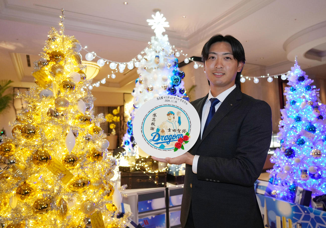 会見場の名古屋マリオットアソシアホテルからプレゼントされた記念絵皿を手に笑顔を見せる吉田（撮影・森本幸一）