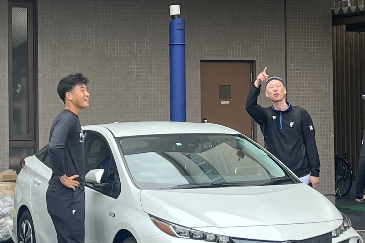 フロントガラスが割れた車の前で、打球の軌道を確認する日本ハム森本外野守備走塁コーチ（右）。左は明瀬（撮影・永野高輔）
