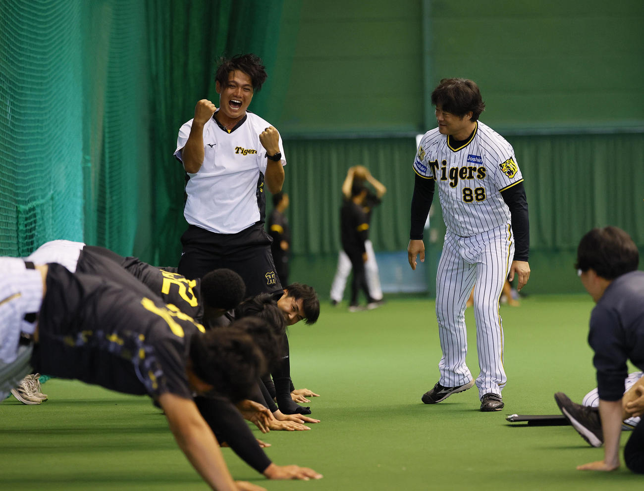 安藤投手コーチ　（右）とのじゃんけんに勝ちガッツポーズをする阪神西純。体幹トレーニングの秒数が短縮した（撮影・藤尾明華）