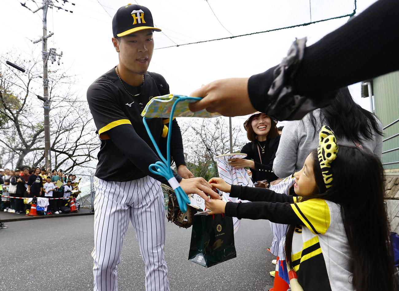 秋季キャンプ最終日、ファンからのプレゼントを受け取りメイン球場に向かう阪神佐藤輝（撮影・藤尾明華）