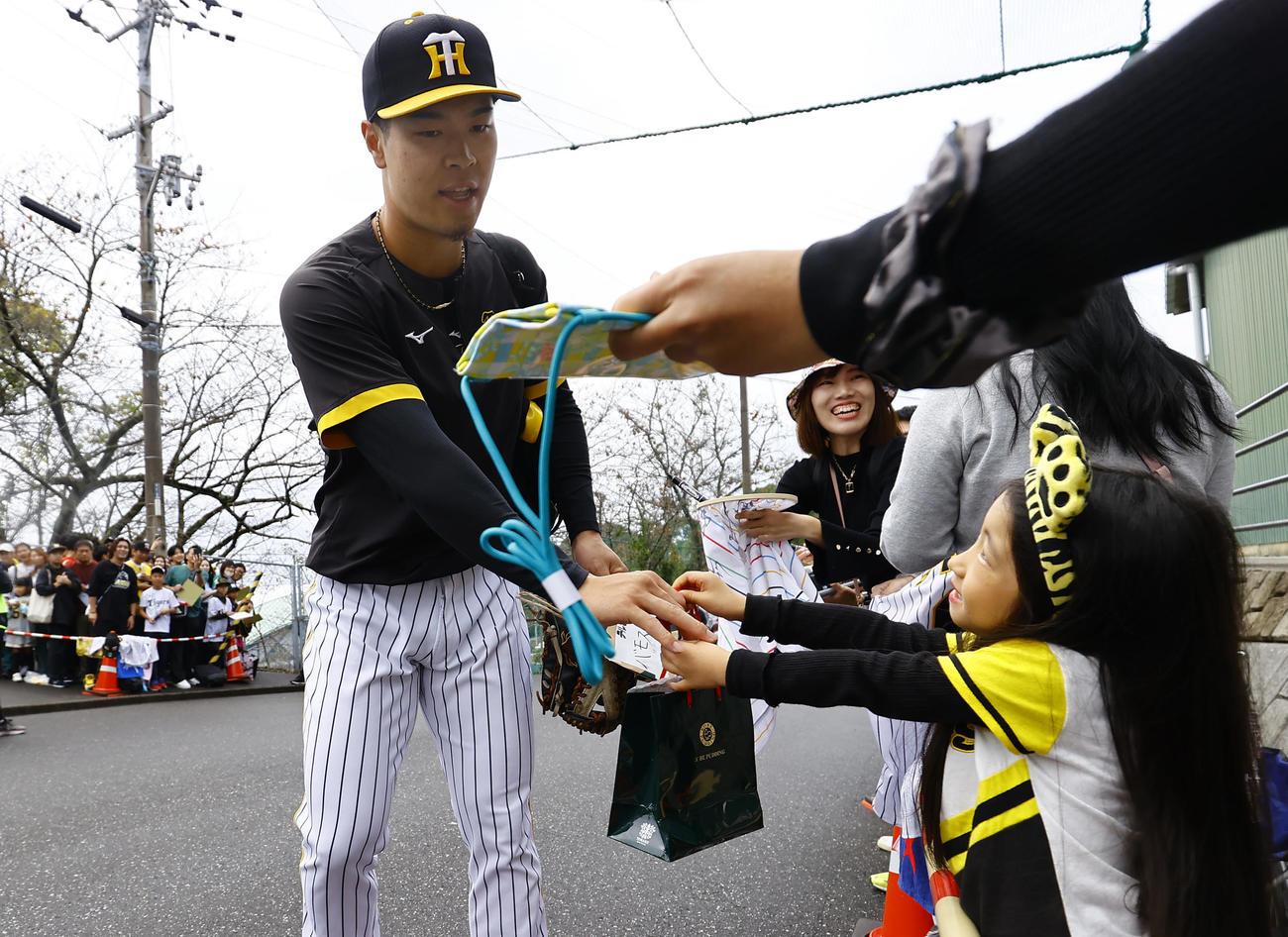 秋季キャンプ最終日、ファンからのプレゼントを受け取りメイン球場に向かう阪神佐藤輝（撮影・藤尾明華）