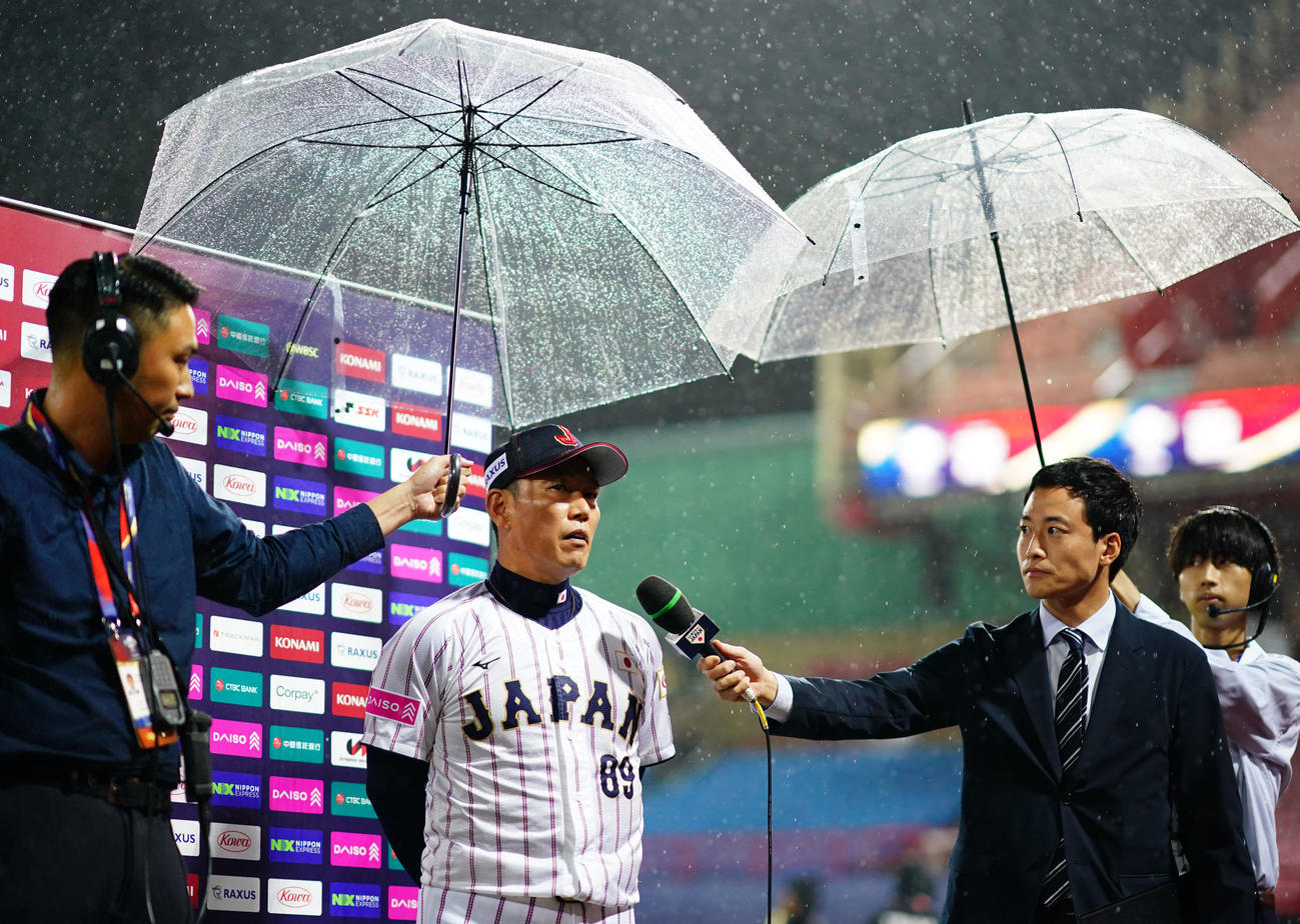 日本対キューバ　かさの下で取材に応じる井端監督（撮影・横山健太）