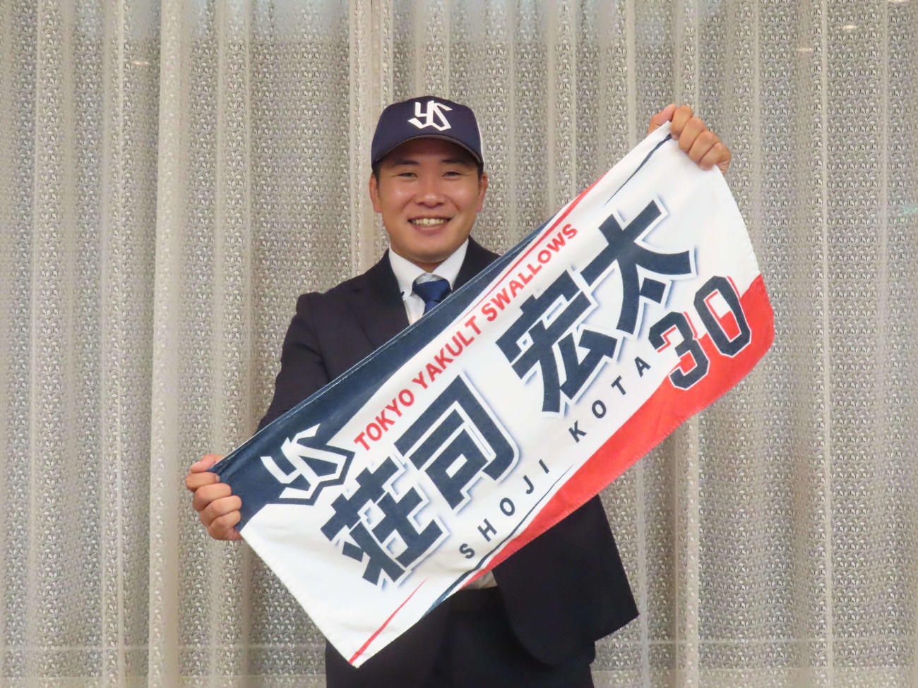 仮契約を終えたヤクルトドラフト3位の荘司は、自身の応援タオルを手に笑顔で写真に納まる（撮影・水谷京裕）