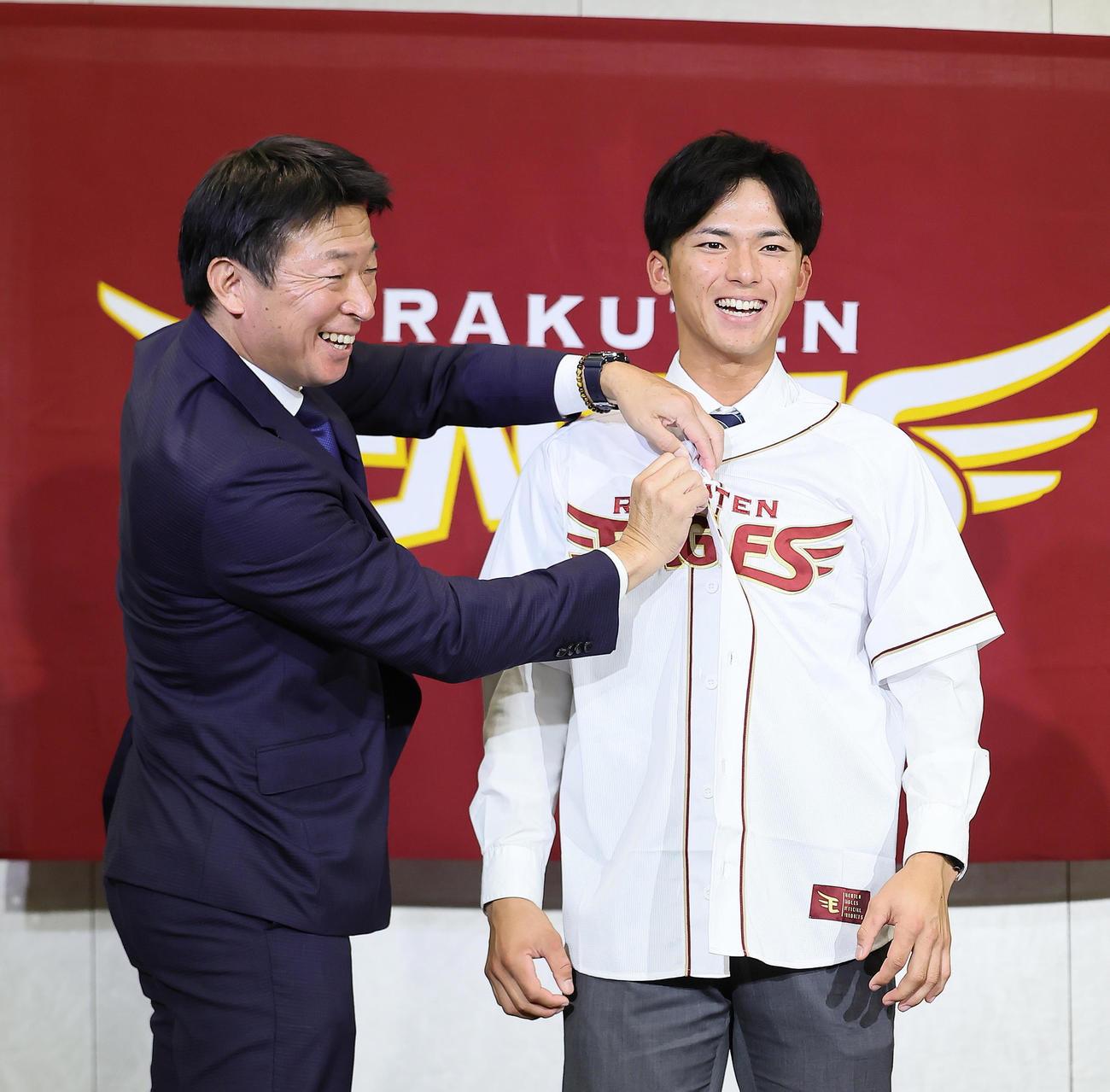 入団交渉後の会見を終えた楽天ドラフト1位の明大・宗山（右）は沖原担当スカウトからユニホームを着せてもらう（撮影・足立雅史）