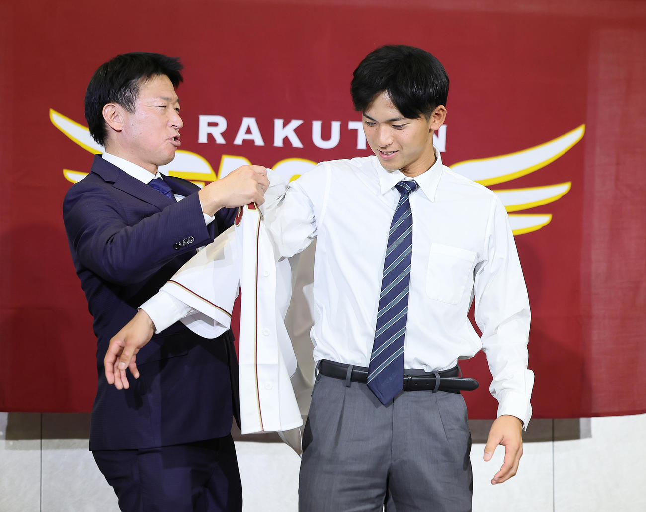 入団交渉後の会見を終えた楽天ドラフト1位の明大・宗山（右）は沖原担当スカウトからユニホームを着せてもらう（撮影・足立雅史）