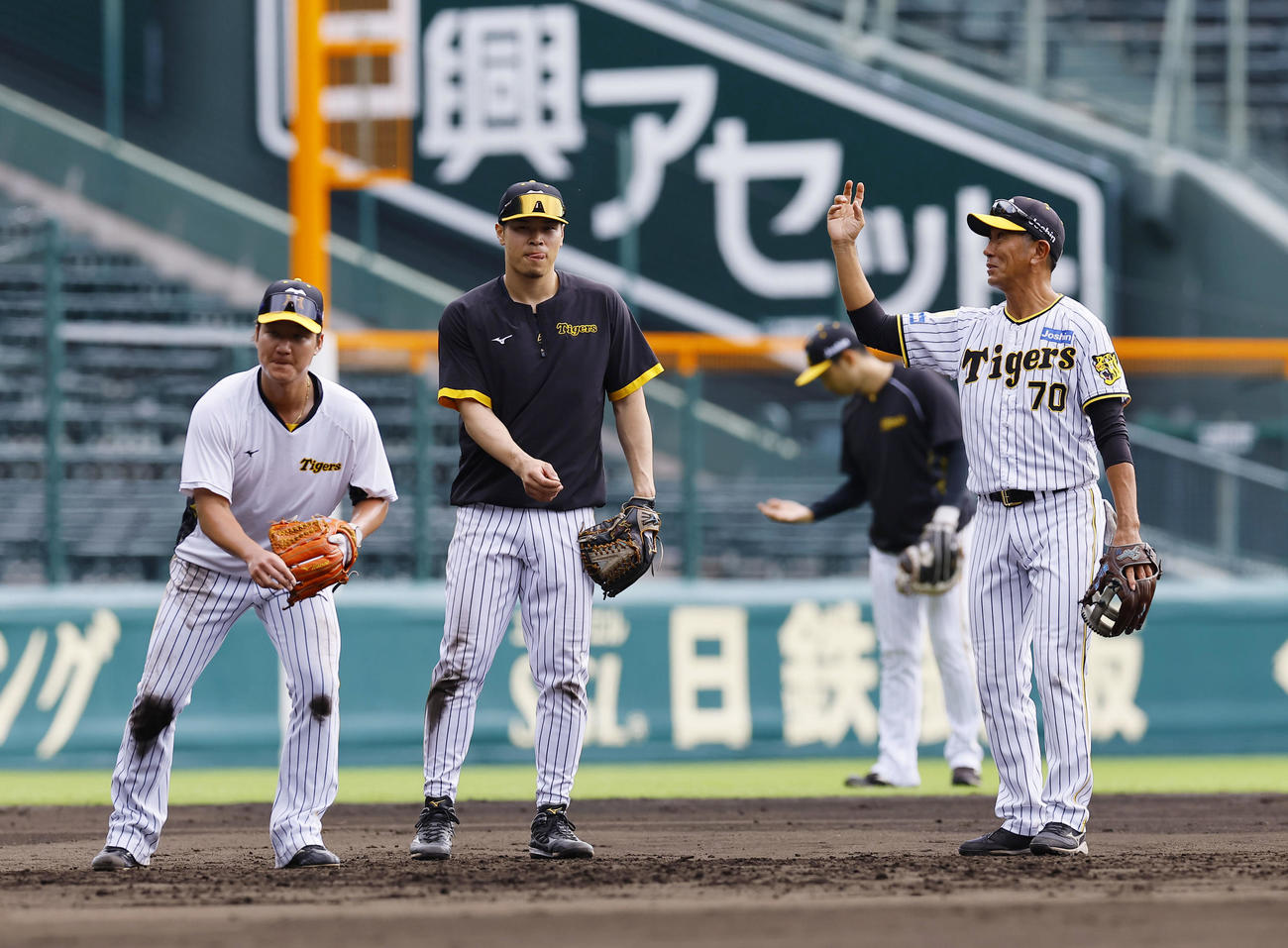 10月27日、全体練習後に田中守備走塁コーチ（右端）の指導を受けながら、ノックを受ける阪神佐藤輝と渡辺（左端）