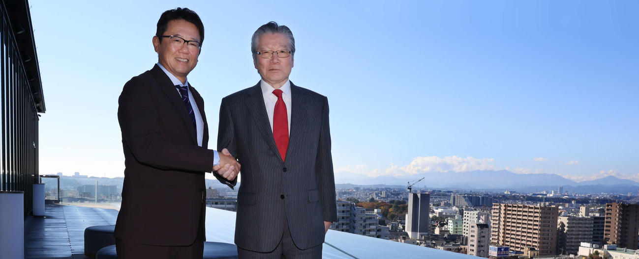 立川「SORANO HOTEL」で、プールを背に握手する立飛の村山正道社長（右）と古田敦也理事長（撮影・浅見桂子）