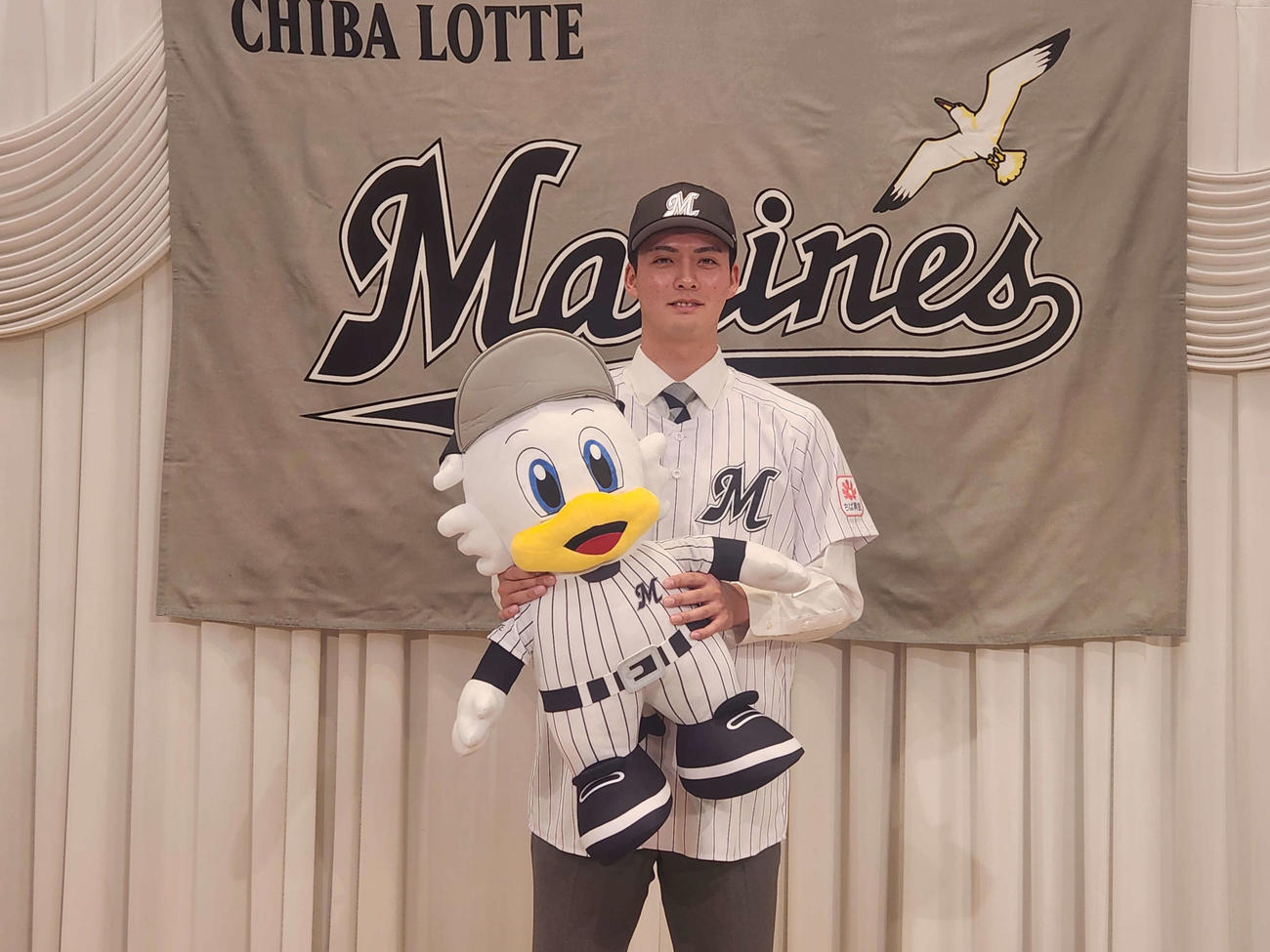 仮契約を終え、ロッテのマスコット、マーくんのぬいぐるみを抱くロッテ2位の東洋大・一條（撮影・保坂淑子）