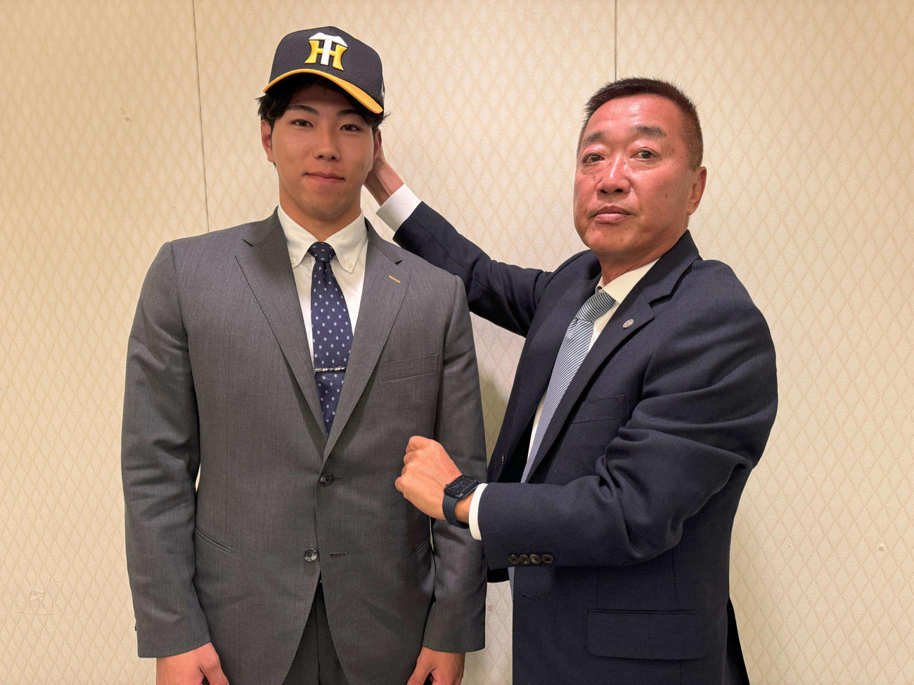 阪神育成1位の四国IL徳島の工藤（左）は仮契約を結び、山本スカウトから帽子をかぶせてもらう（球団提供）