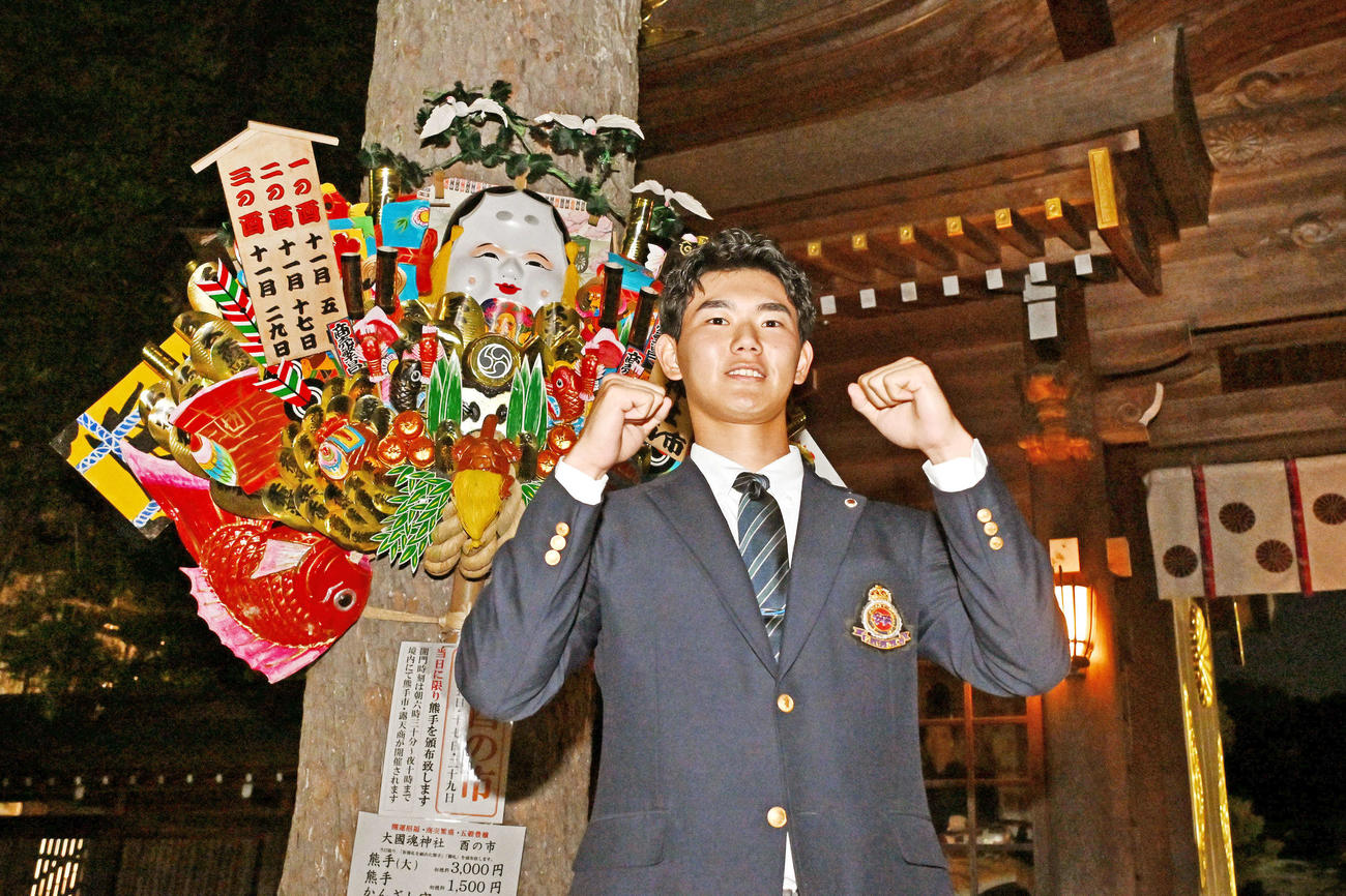 大国魂神社で仮契約を行った日本ハムドラフト3位の明大・浅利は熊手の前でガッツポーズする（撮影・滝沢徹郎）