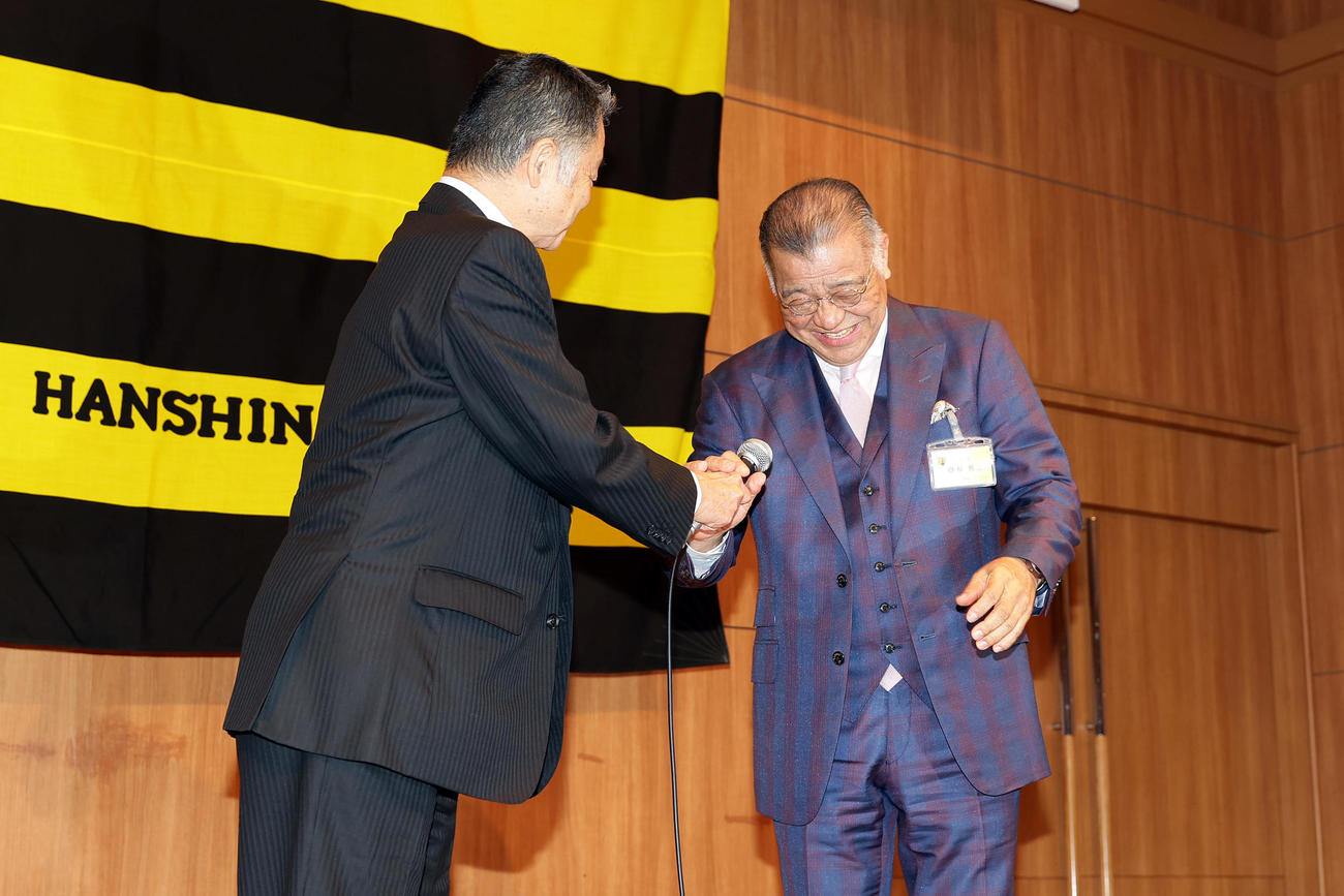 川藤前会長（左）からマイクを受け取る阪神掛布OB新会長（撮影・前田充）