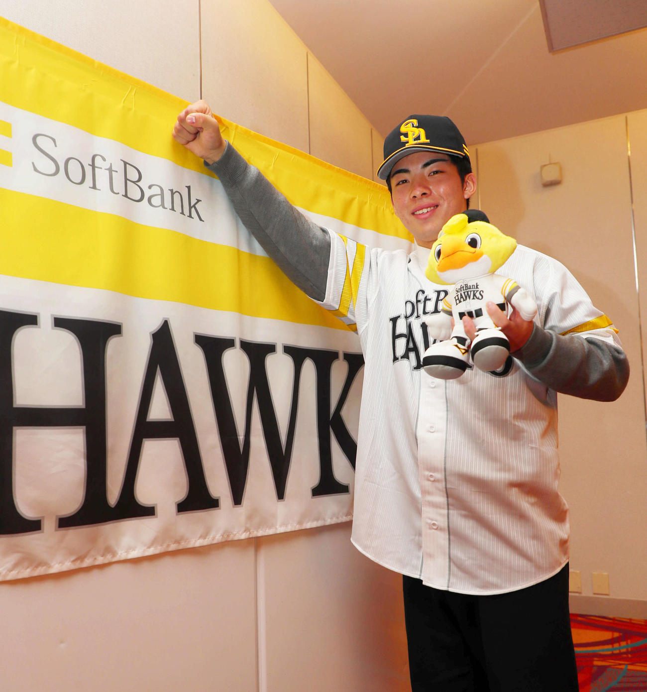 ソフトバンクと仮契約を結んだドラフト1位の村上は、球団旗の前でガッツポーズ（撮影・宮崎幸一）