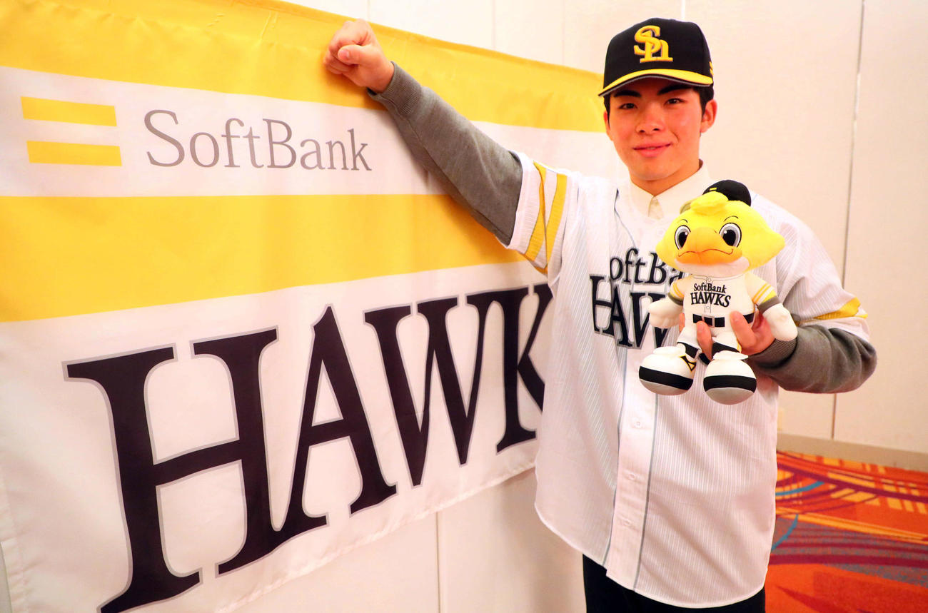 ソフトバンクと仮契約を結んだドラフト1位の村上は、球団旗の前でガッツポーズ（撮影・宮崎幸一）