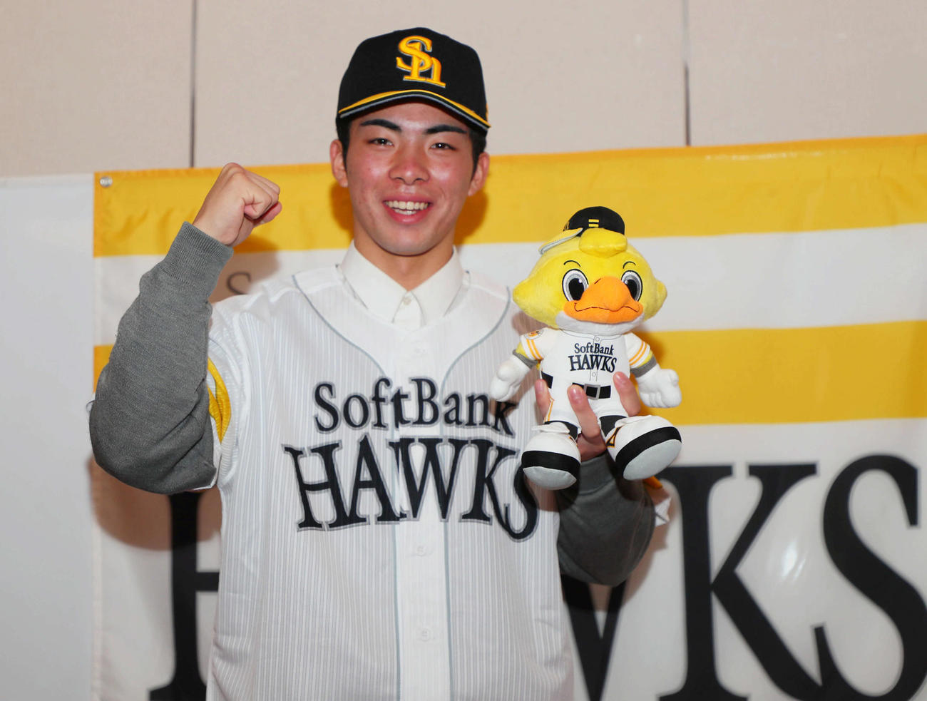 ソフトバンクと仮契約を結んだドラフト1位の村上は、球団旗の前でガッツポーズ（撮影・宮崎幸一）