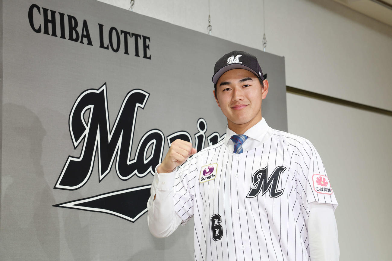 背番号「6」ユニホームを羽織り笑顔でガッツポーズするロッテドラフト1位の青学大・西川（撮影・宮地輝）