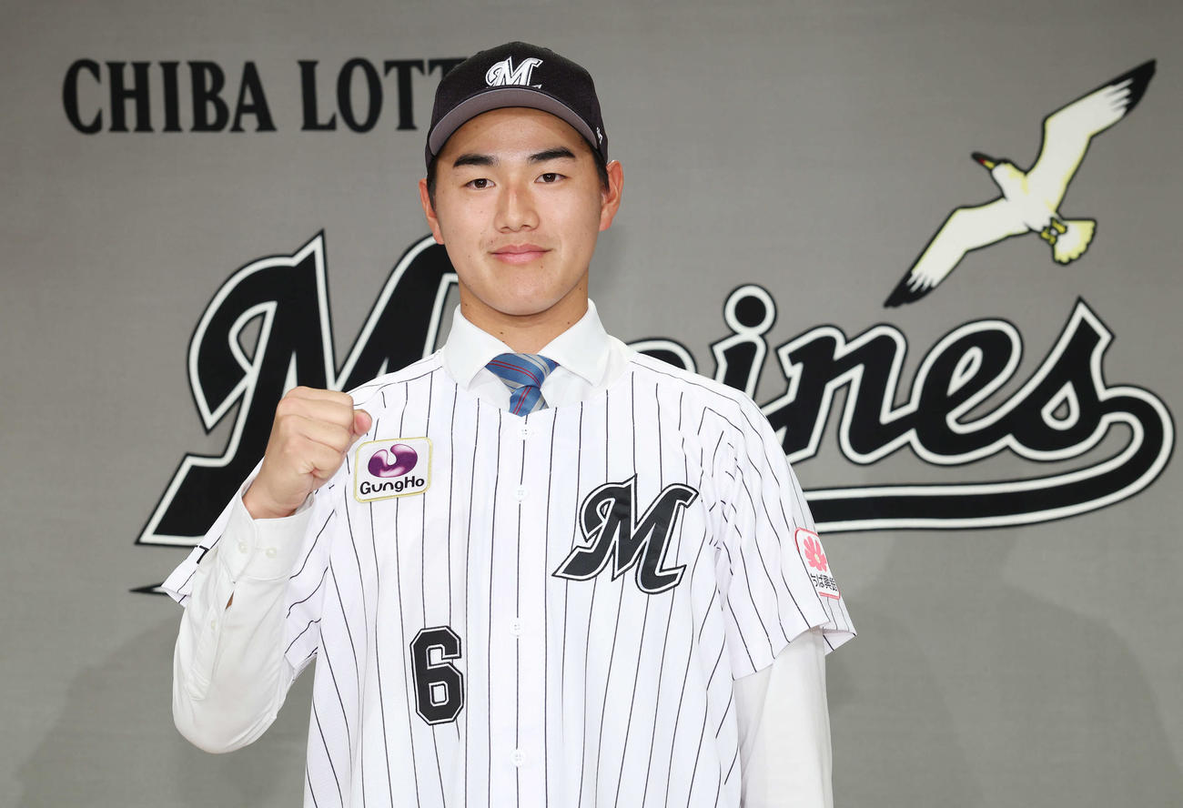 背番号「6」ユニホームを羽織り笑顔でガッツポーズするロッテドラフト1位の青学大・西川（撮影・宮地輝）