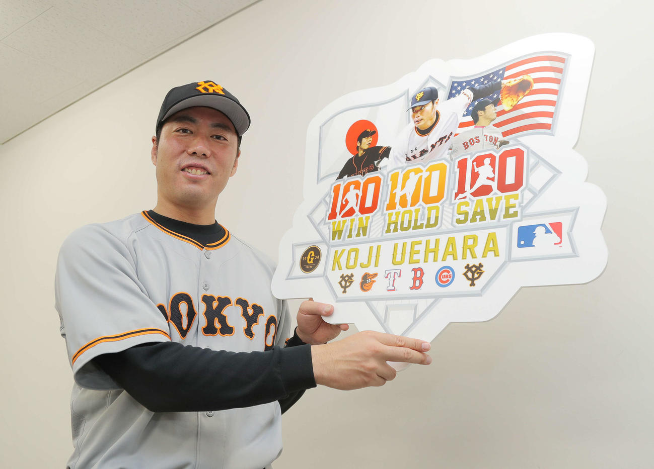 日米通算100勝100セーブ100ホールドを達成し、ボードを掲げる上原浩治（2018年7月20日撮影）