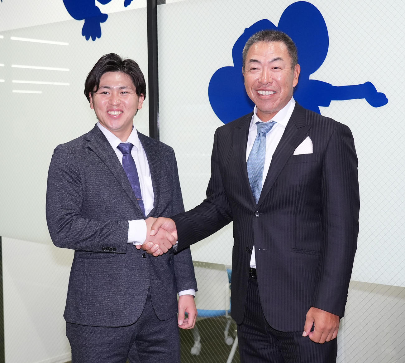 所用で球団事務所に訪れた井上監督と握手を交わす三浦（左）（撮影・森本幸一）