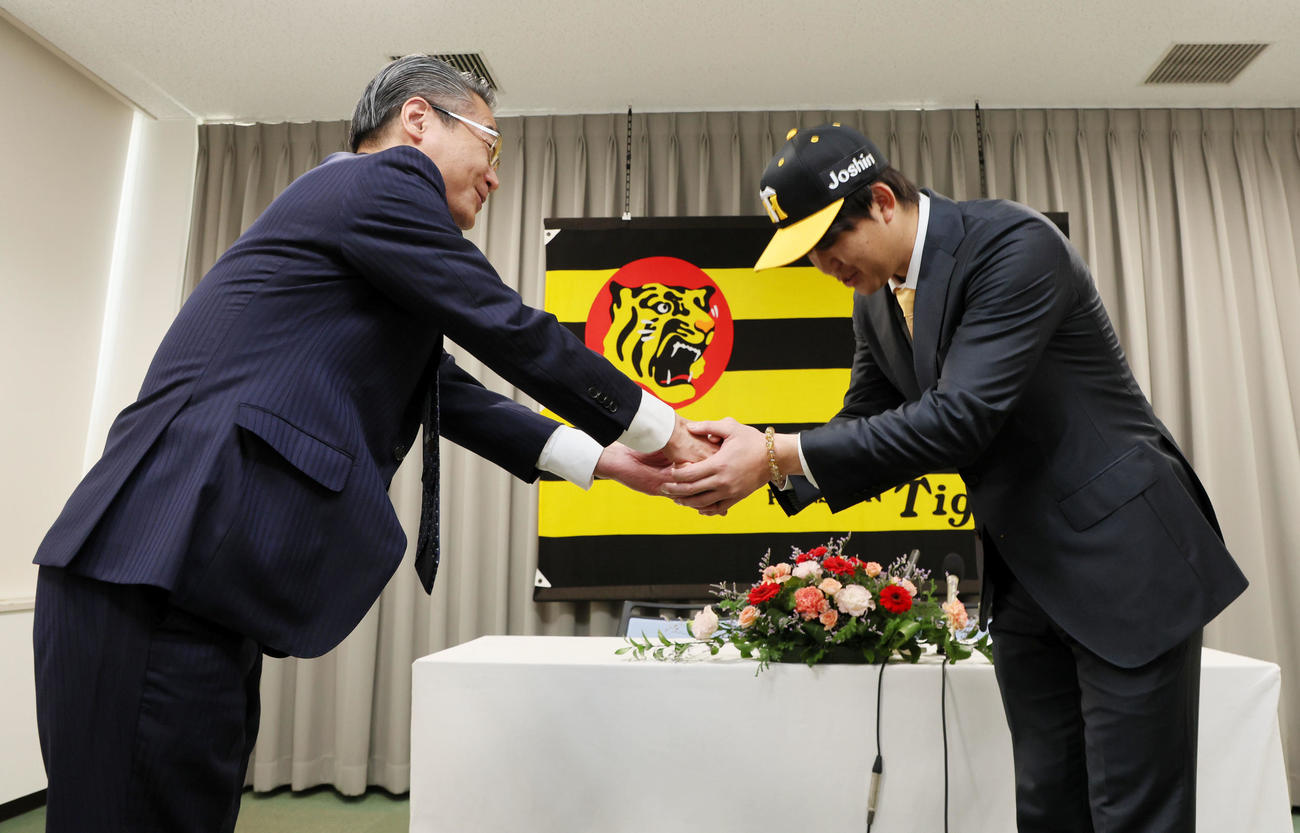 入団会見で嶌村球団本部長（左）とがっちり握手する楠本（撮影・加藤哉）