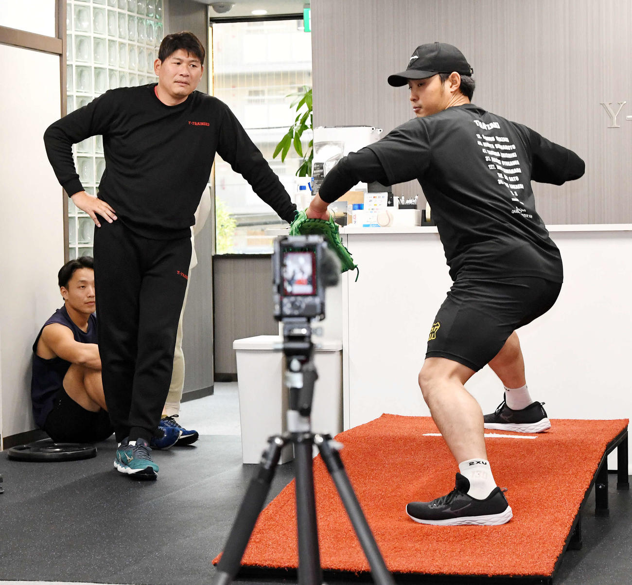 阪神佐藤蓮（右）は村上幸史氏から投てき動作の指導を受ける（撮影・前岡正明）