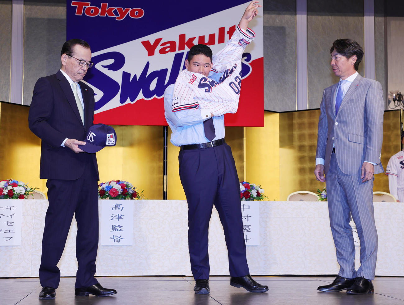 ヤクルトの新入団選手発表でユニホームを着用する根岸。左は林田社長、右は高津監督（撮影・野上伸悟）