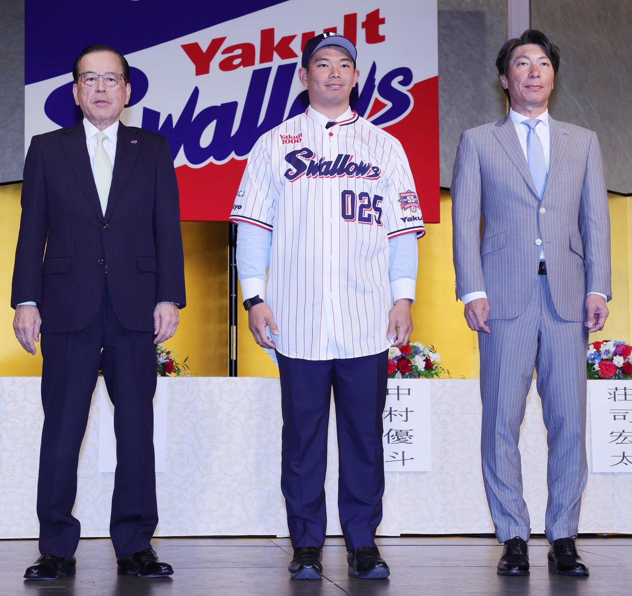ヤクルトの新入団選手発表でユニホームを着用する根岸。左は林田社長、右は高津監督（撮影・野上伸悟）