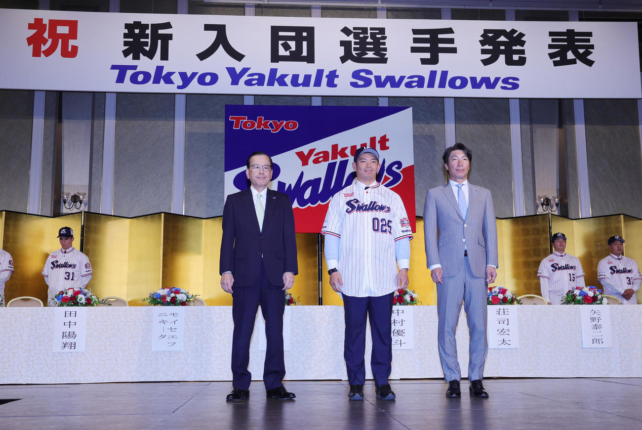 ヤクルトの新入団選手発表でユニホームを着用する根岸。左は林田社長、右は高津監督（撮影・野上伸悟）