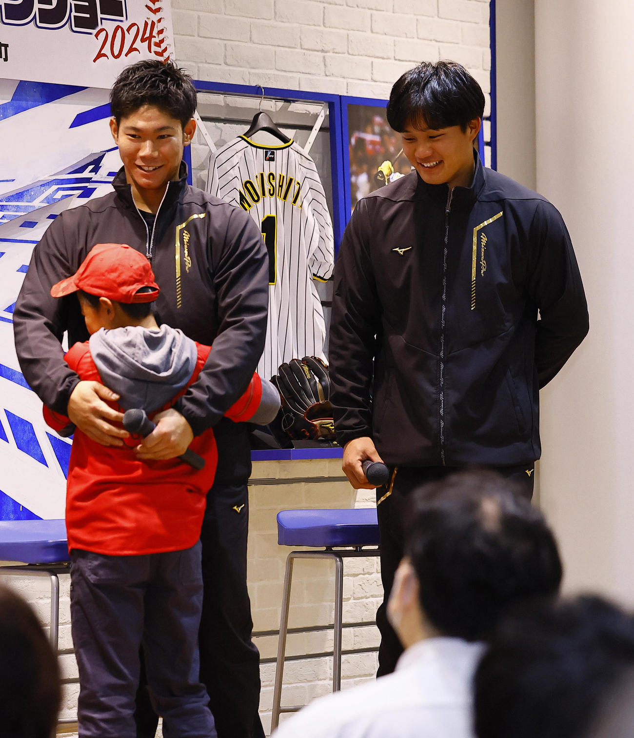 ミズノのイベントに参加し、子どもを抱きしめる広島坂倉（左）。右は阪神森下（撮影・藤尾明華）