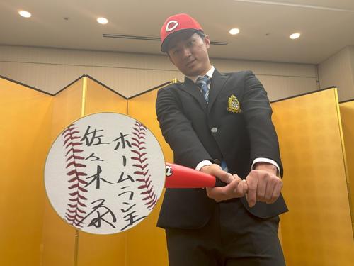 仮契約を終えてカメラマンの要望に応えてポーズをとる広島ドラフト1位の青学大・佐々木(撮影・前原淳)
