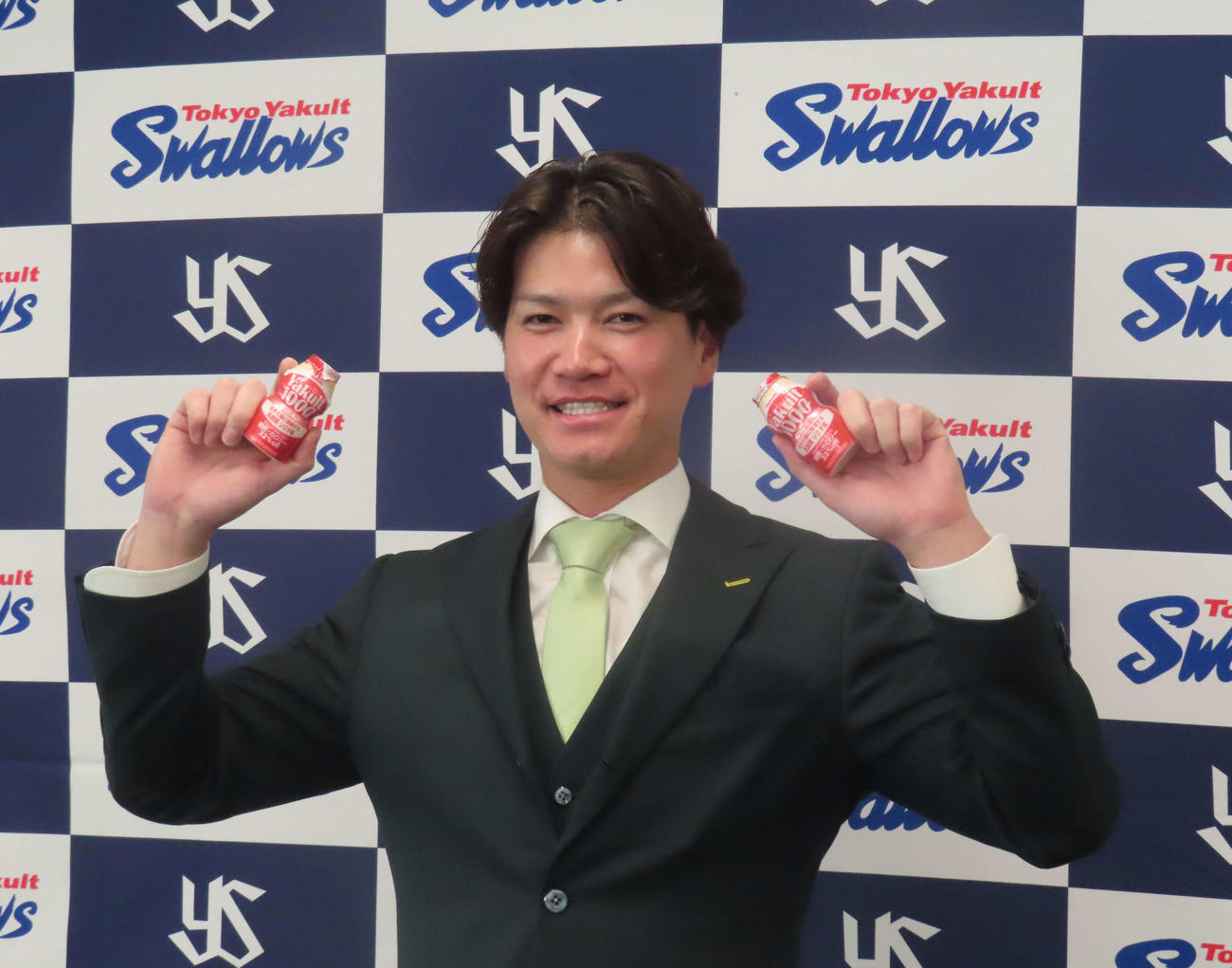 会見に臨み、ヤクルトを手に笑顔を見せるヤクルト鈴木康（撮影・水谷京裕）